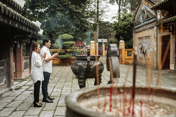 Side view man woman praying temple with burning incense