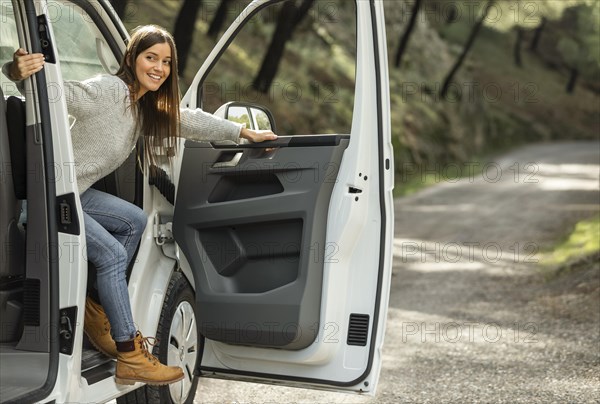 Side view smiley woman getting out car while road trip