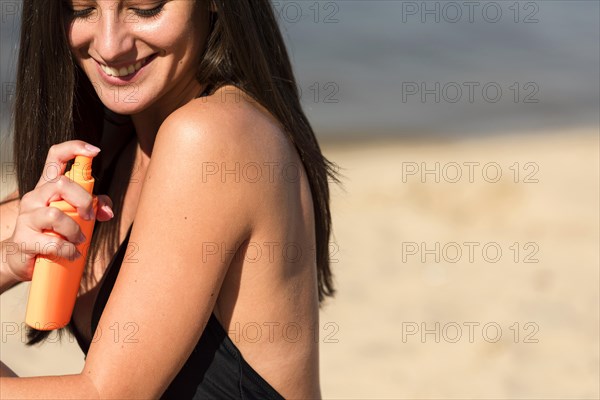 Side view woman applying sunscreen beach