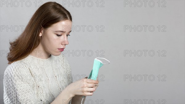 Side view woman holding medical mask her hands with copy space