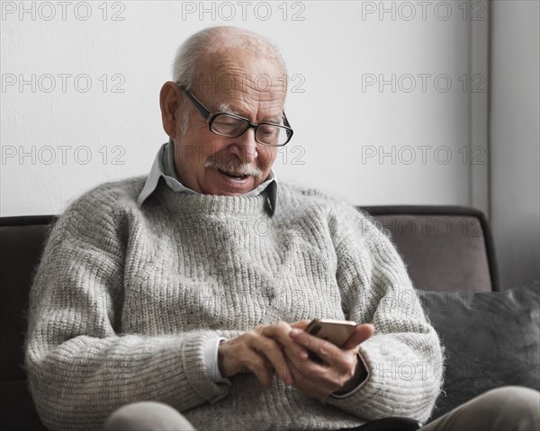 Smiley old man using smartphone nursing home