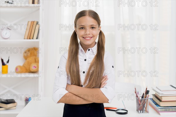 Smiling elementary school girl standing with arms crossed