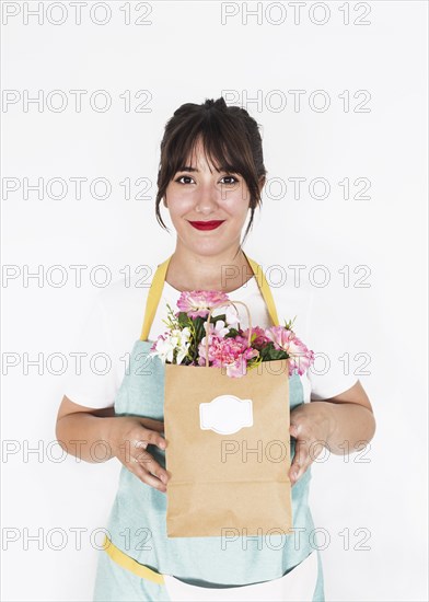 Smiling female florist holding paper bag full fresh flowers