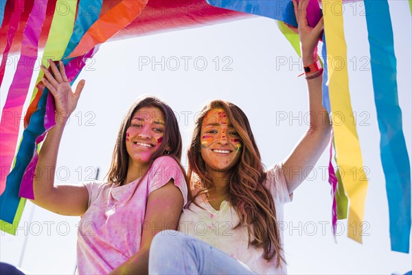 Smiling portrait young women with holi color their face looking camera
