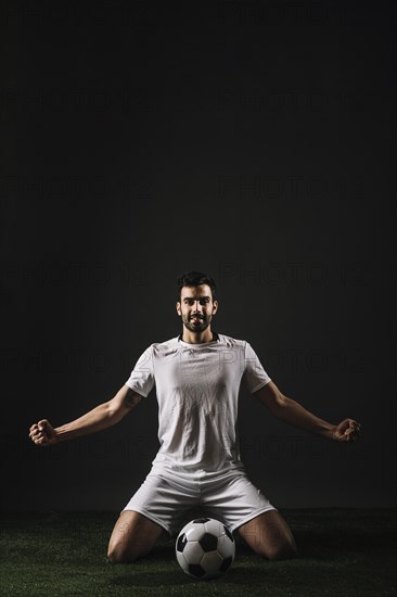 Smiling sportsman sitting near ball