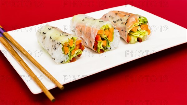 Steamed spring rolls arrange white plate with chopstick red surface