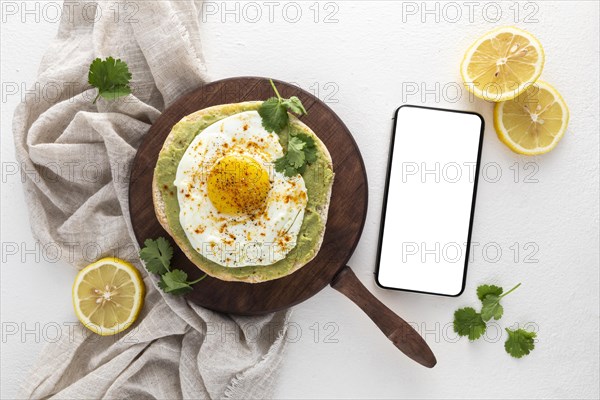 Top view pita with avocado spread fried egg with blank phone