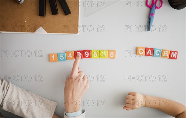 Top view tutor teaching child desk about numbers letters