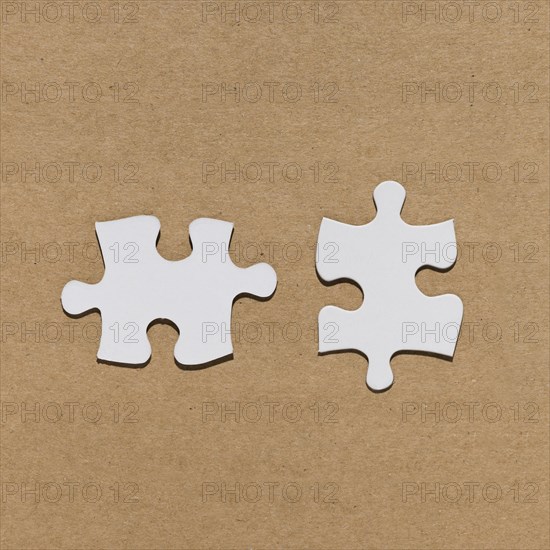 White jigsaw puzzle piece brown paper textured backdrop
