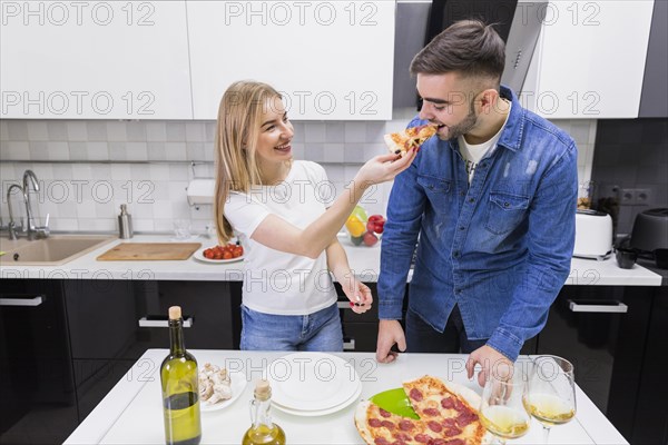 Woman feeding man with pizza kitchen