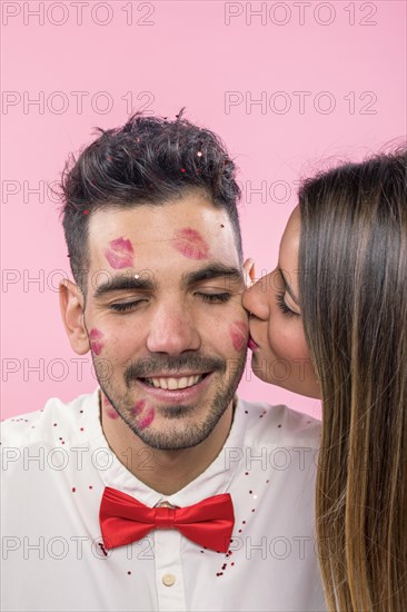 Woman kissing man with lipstick kiss marks cheek