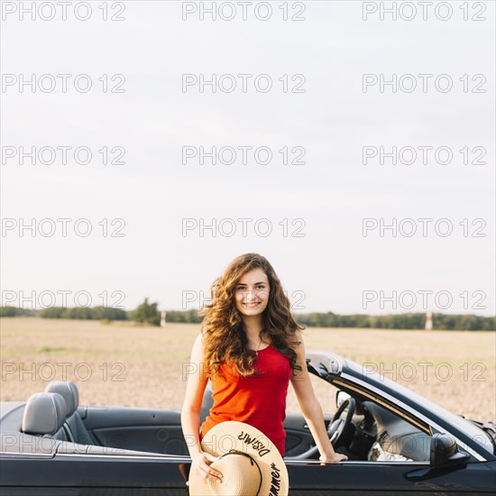 Woman with hat near car