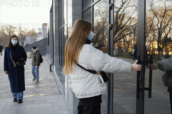 Woman with mask opening door