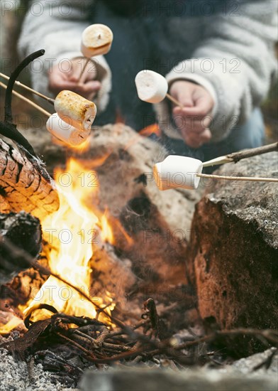 Young woman burning marshmallows camp fire