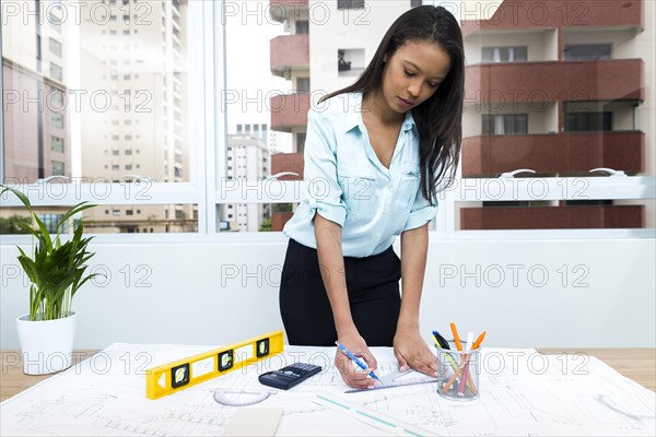 African american lady with pen ruler near plan table with equipments