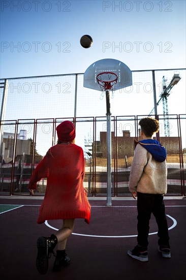 Back view children playing basketball together outdoors