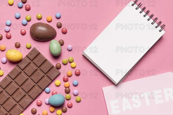 Blank spiral notepad easter word easter eggs multicolored gem candies pink backdrop