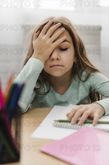 Blonde little girl having headache while doing online classes
