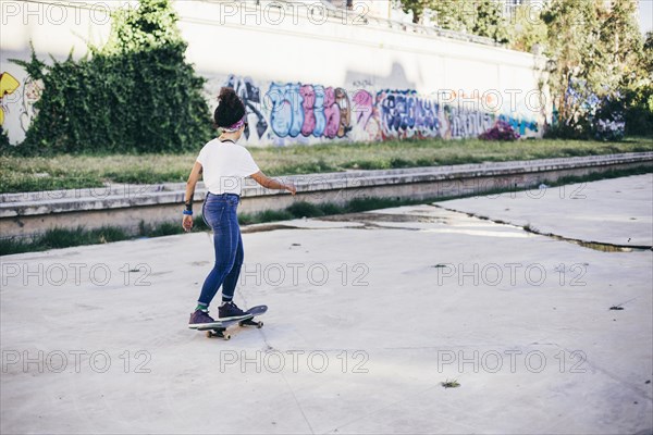 Brunette girl riding skateboard street