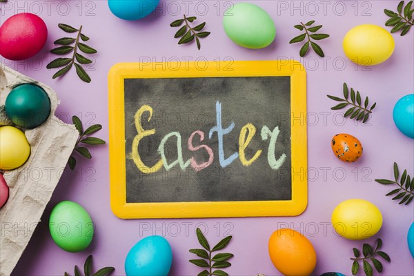 Chalkboard with easter title set colored eggs leaves near container