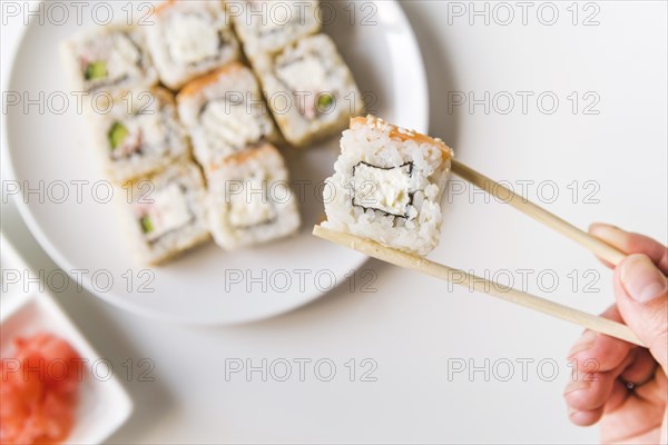 Chopsticks holding sushi roll