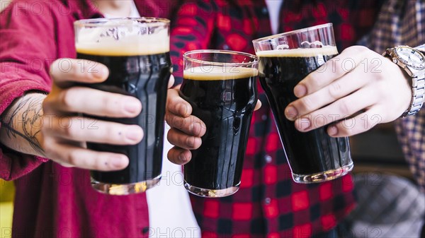 Close up friends clinking beer glasses