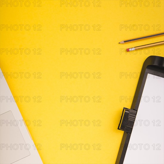 Close up laptop pencils printer tray with blank paper yellow background