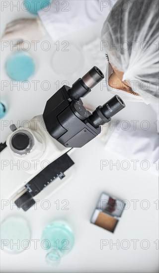 Close up scientist looking through ocular lens