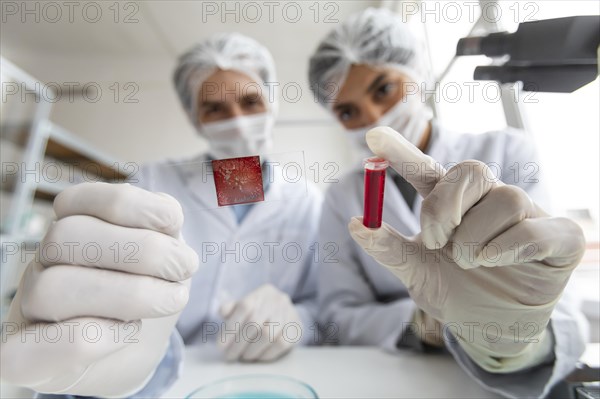 Close up scientists with tube glass slide