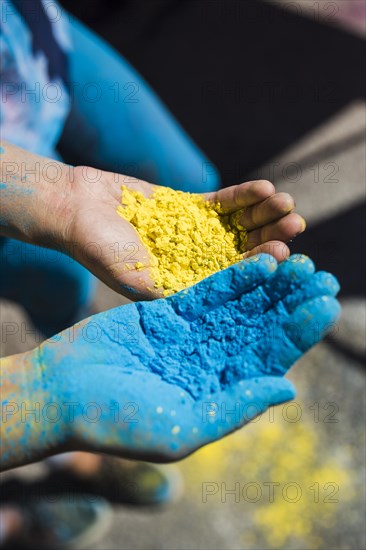 Close up two women s hand holding yellow blue holi color