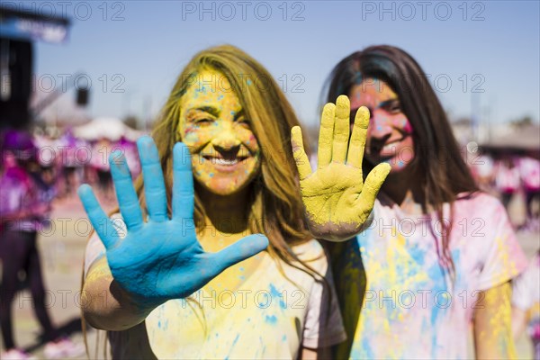 Close up two young women showing their painted hands with holi color