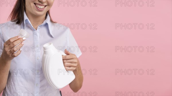 Close up woman holding detergent laundry bottle