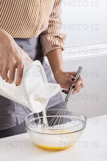 Close up woman s hand adding flour bowl