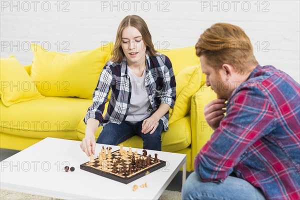 Contemplated man looking her girlfriend playing chess home