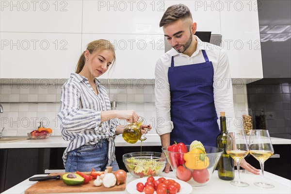 Couple cooking vegetable salad with olive oil