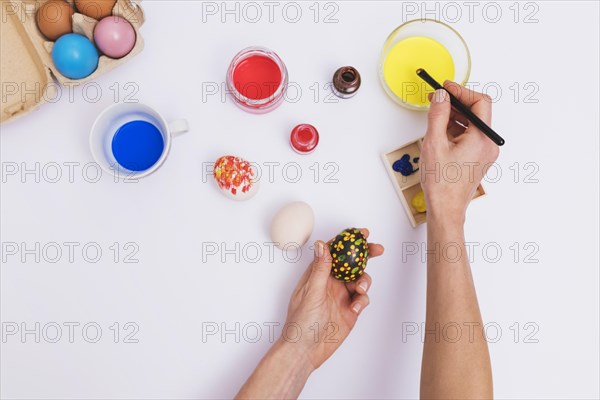 Crop hands painting flowers egg