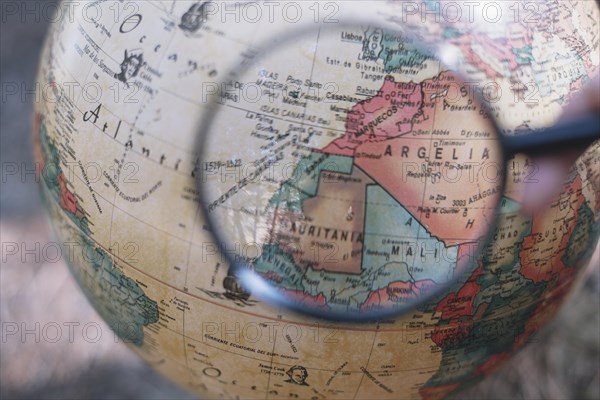 Crop hand with magnifying glass globe