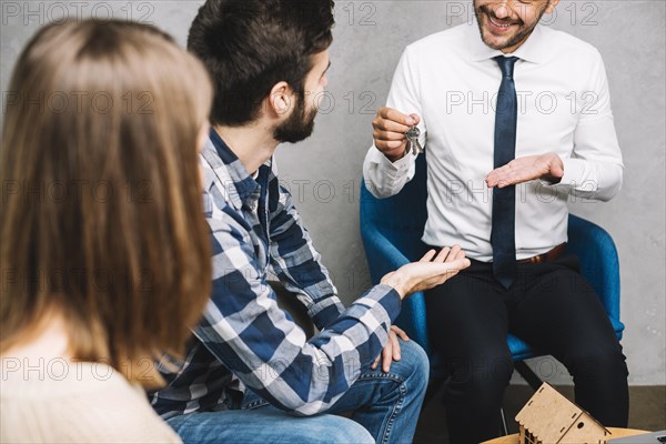 Crop real estate agent giving keys customers