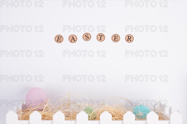 Easter word near bright eggs hay box
