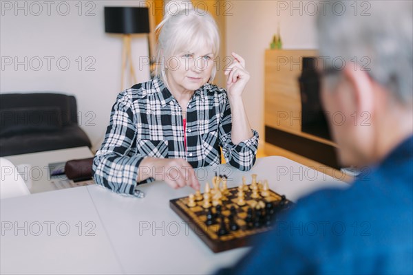 Elderly couple playing chess retirement home