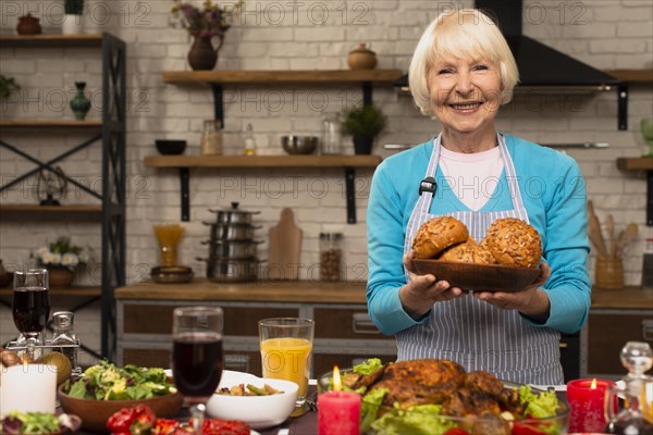 Elderly woman holding plate with bread looking camera