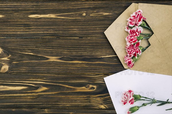 Elevated view carnation flowers envelop brown table