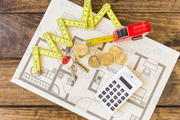 Elevated view measure tape stacked coins key calculator blueprint