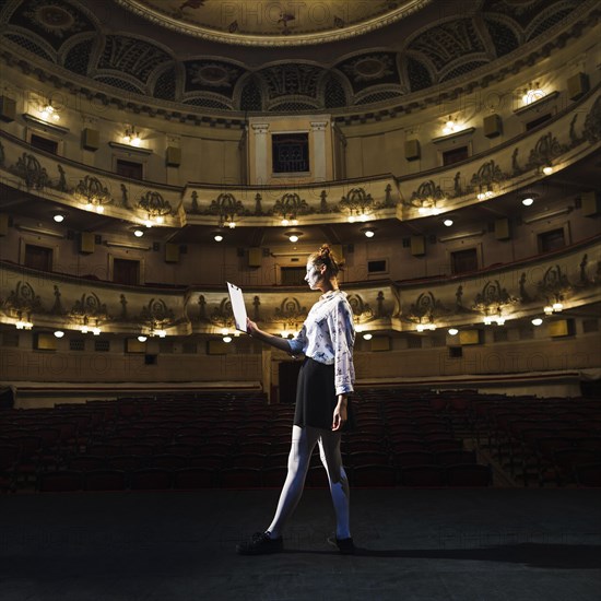 Female mime reading manuscript empty auditorium