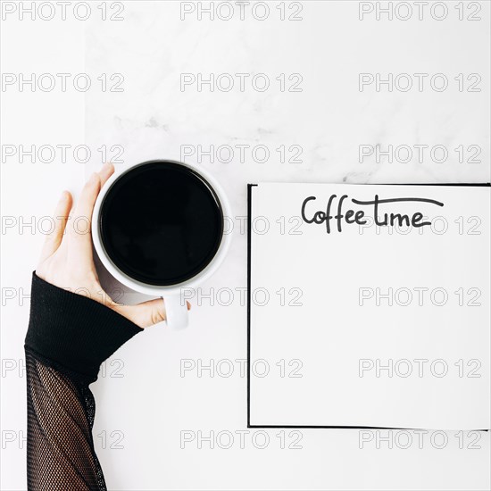 Female s hand holding coffee cup with handwritten text notebook desk