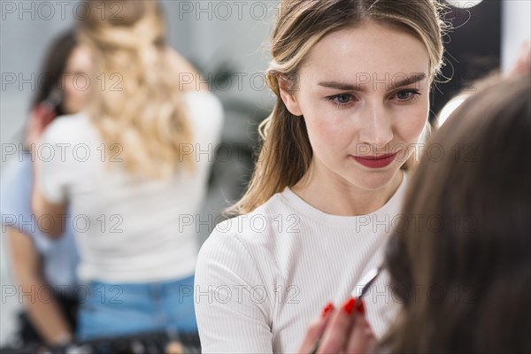 Female visagiste putting makeup client