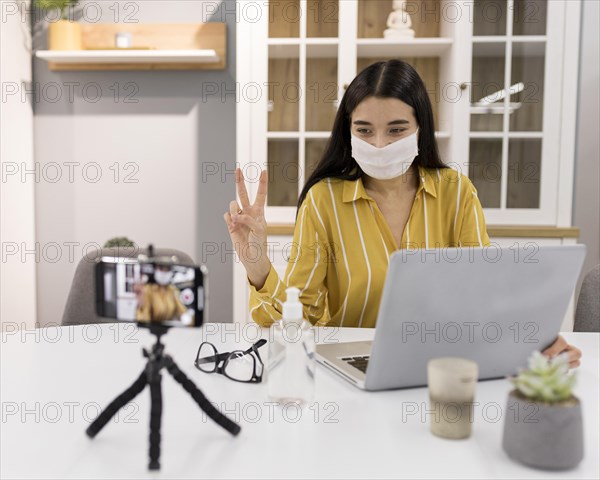 Female vlogger home with smartphone laptop