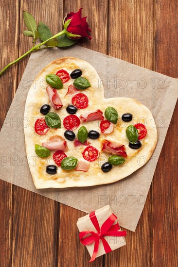 Flat lay heart shaped pizza wooden table