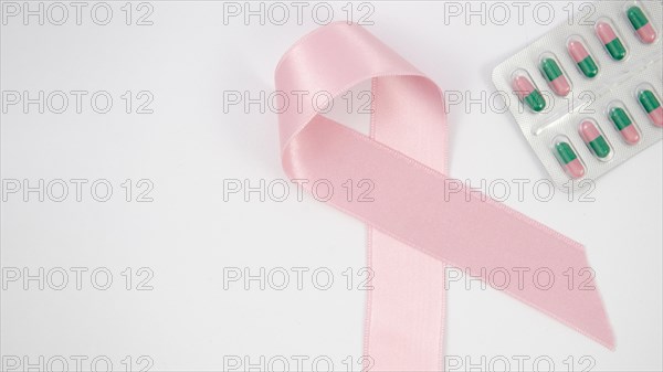 Flat lay pink ribbon pills arrangement