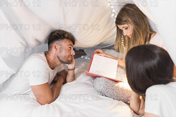 Friends looking album sitting bed white curtain